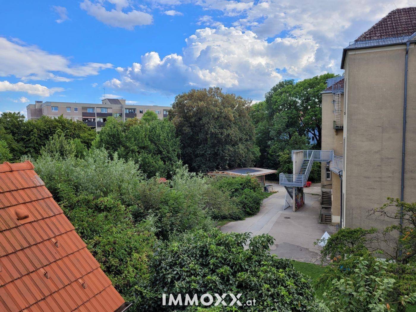 Weitläufiger Blick auf eine grüne Parkanlage mit Spielplatz und umliegenden Gebäuden.