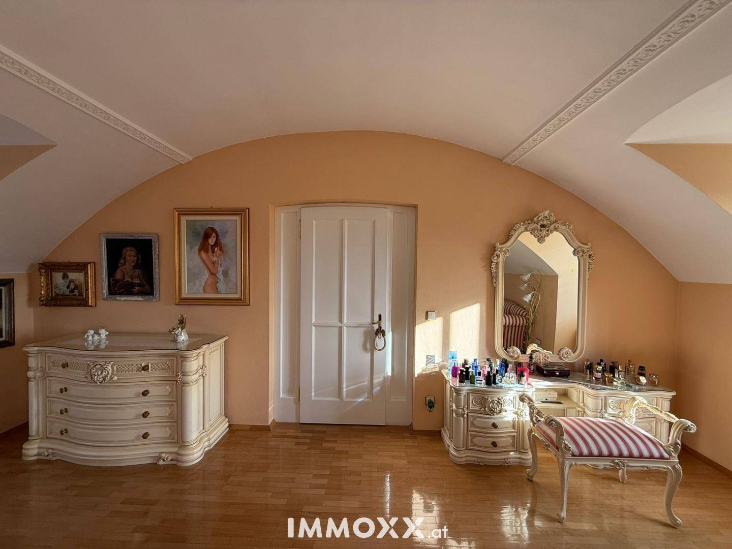 Eleganter Ankleidebereich mit großem Zierspiegel, Schminktisch und Kommode in hellem Design.
