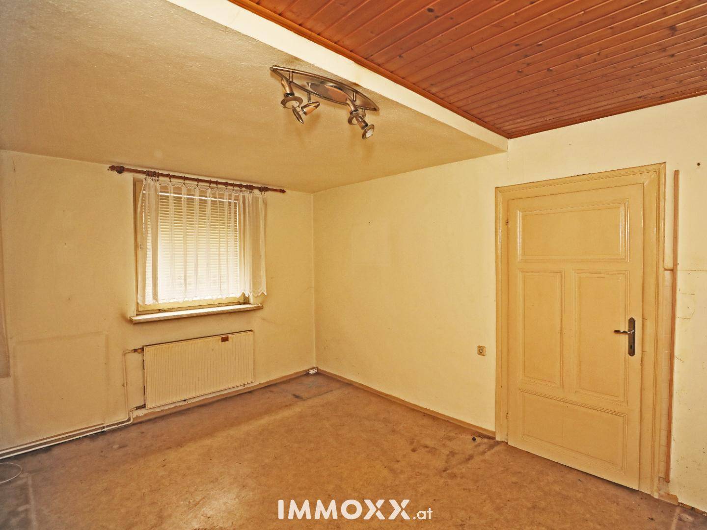 Gemütlicher Raum mit Holzdecke, Fenster und Tür, bietet Potenzial für ein Schlafzimmer.