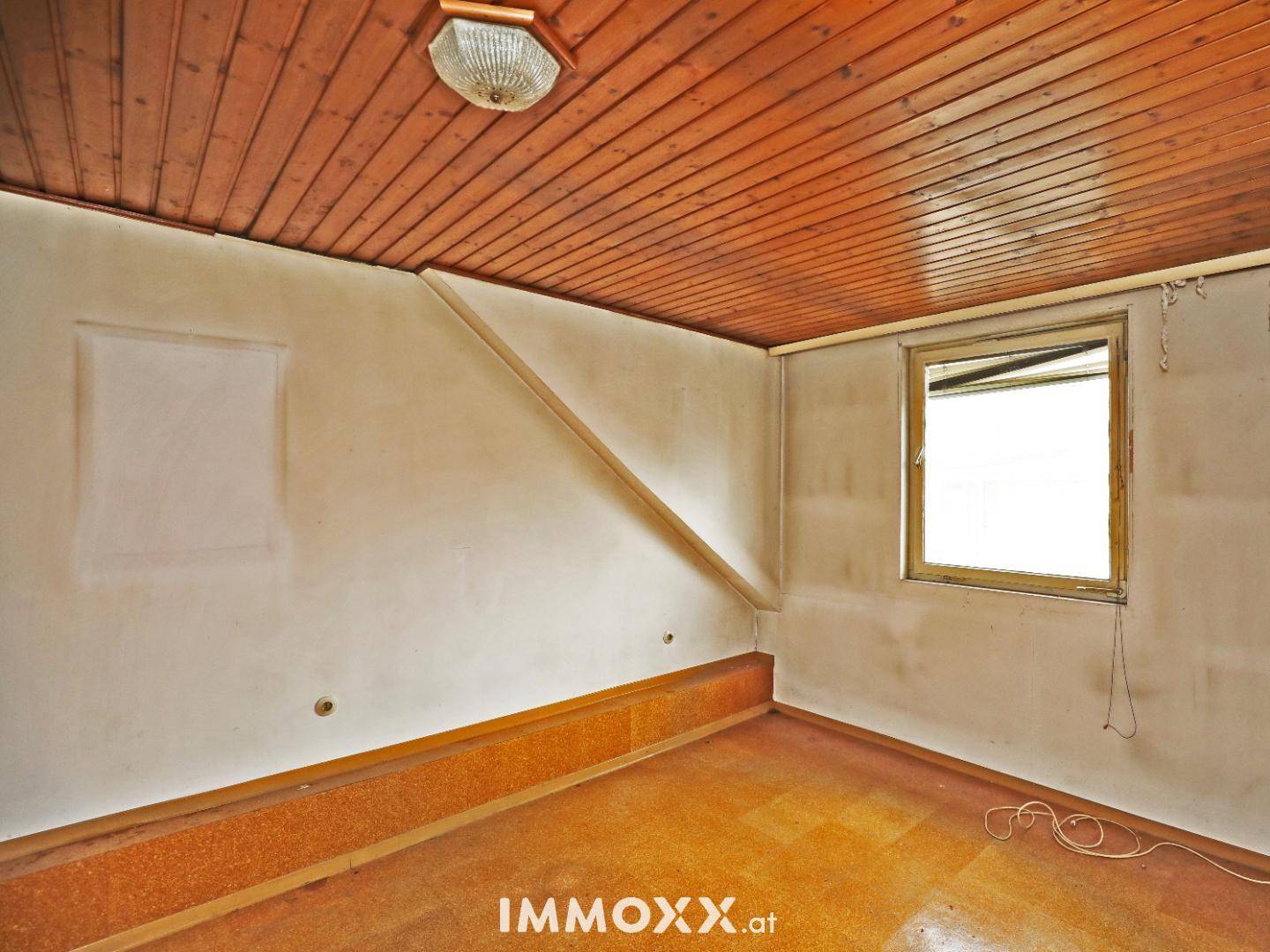Kleiner Raum mit Holzdecke und schräger Wand, ideal als Schlaf- oder Kinderzimmer.