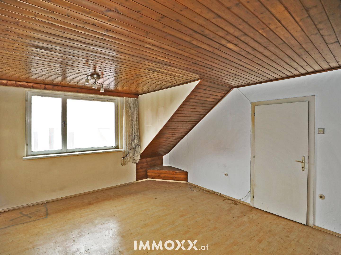 Geräumiger Raum mit Holzdecke und Treppenaufgang, bietet Zugang zu weiteren Etagen.
