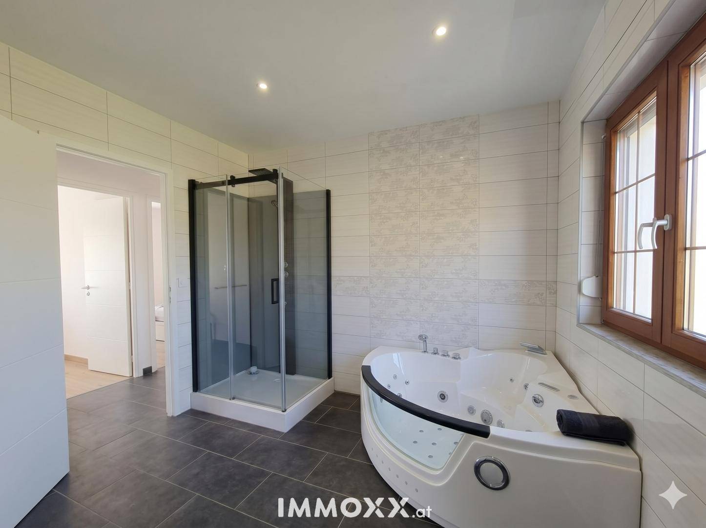Modernes Badezimmer mit Eck-Whirlpool, separater Duschkabine und großen Fliesen.
