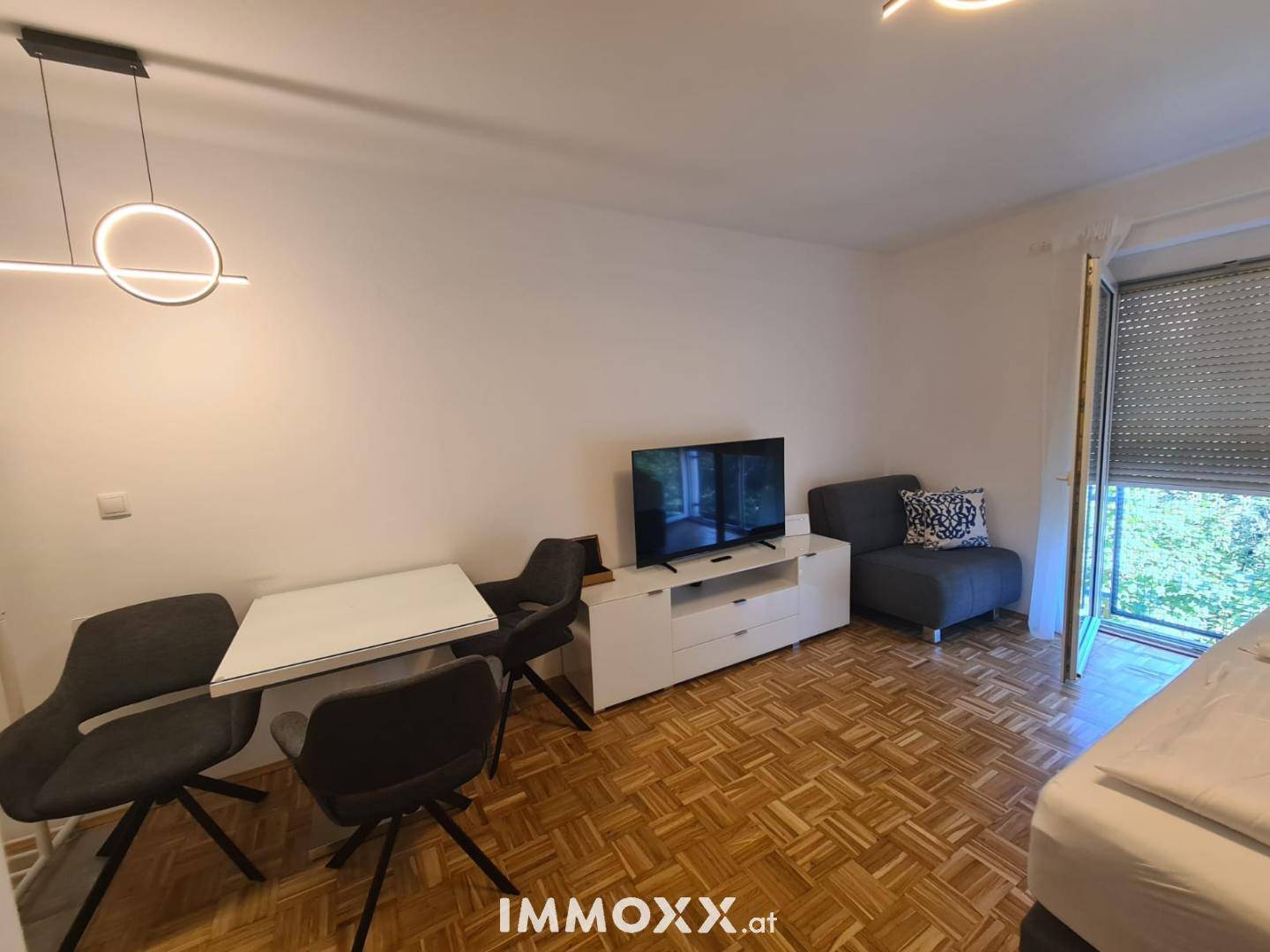 Heller Wohnbereich mit Esstisch, Sofa und Fernseher, ausgestattet mit modernem Parkettboden.