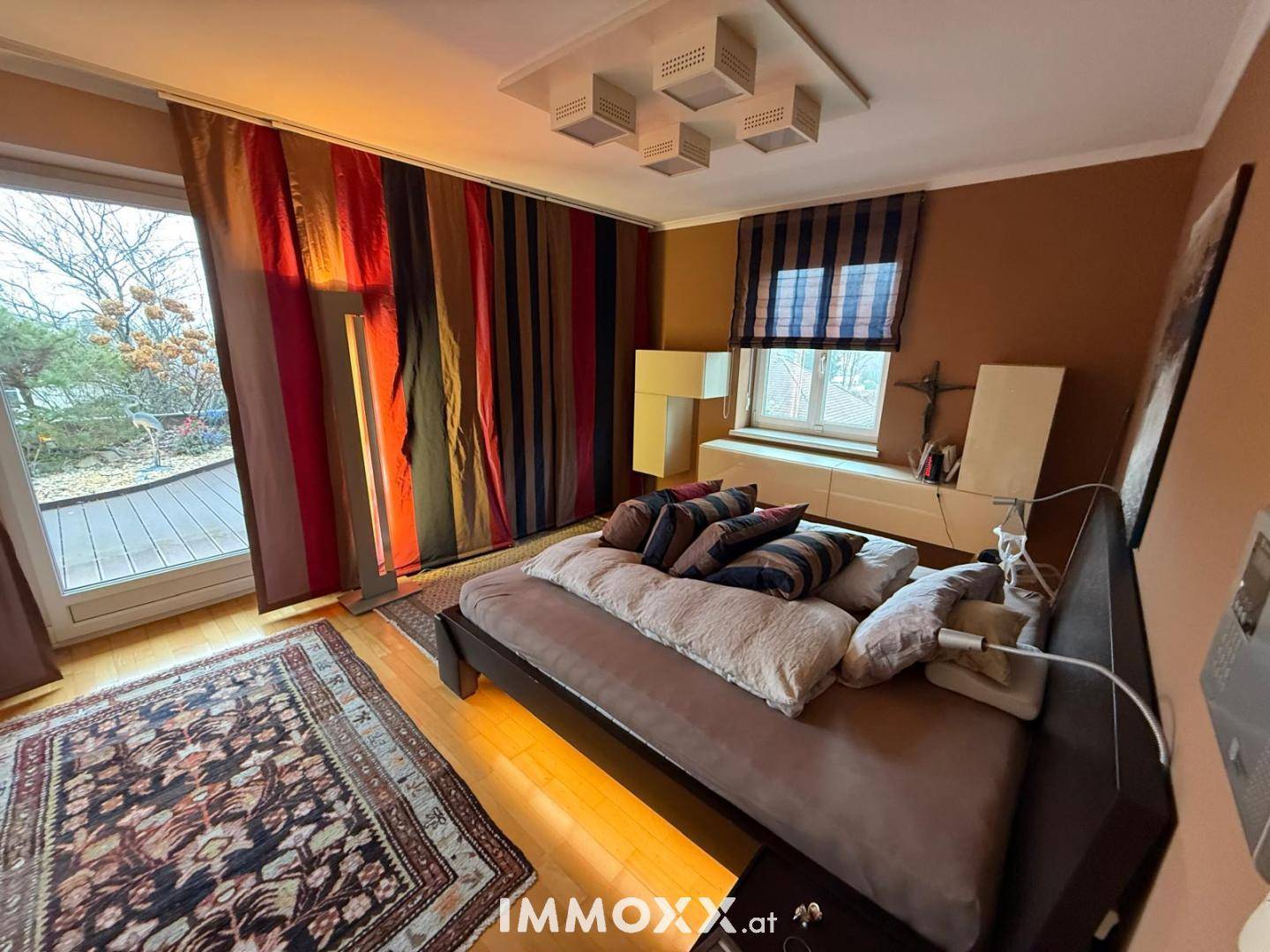Gemütliches Schlafzimmer mit Bett, farbenfrohen Vorhängen und großer Glastür zum Außenbereich.