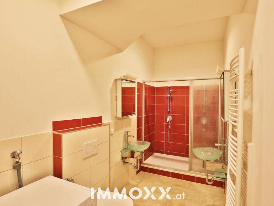 Modernes Badezimmer mit Duschkabine, zwei Waschbecken und beheiztem Handtuchhalter.