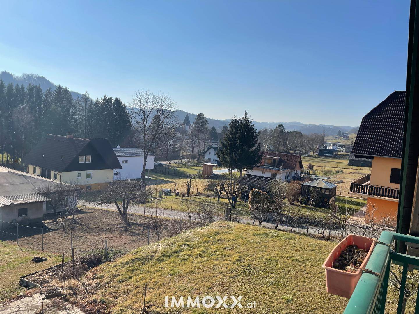 Weitläufiger Ausblick über die ländliche Umgebung mit Häusern, Feldern und Bäumen an einem sonnigen Tag.