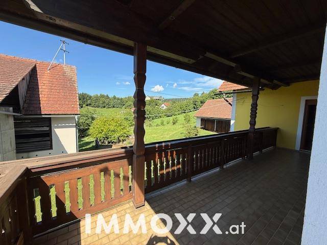 Geräumiger, überdachter Balkon mit traditionellem Holzgeländer und Panoramablick auf die ländliche Umgebung.