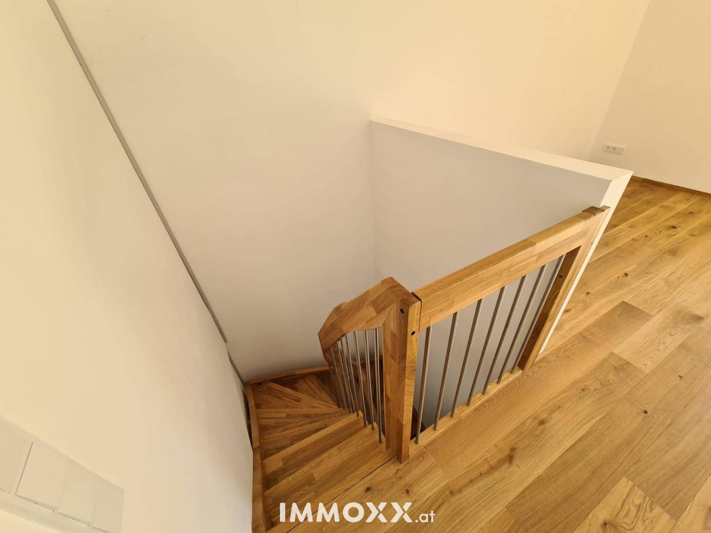 Elegante Holztreppe mit modernem Geländer, die die verschiedenen Ebenen verbindet.