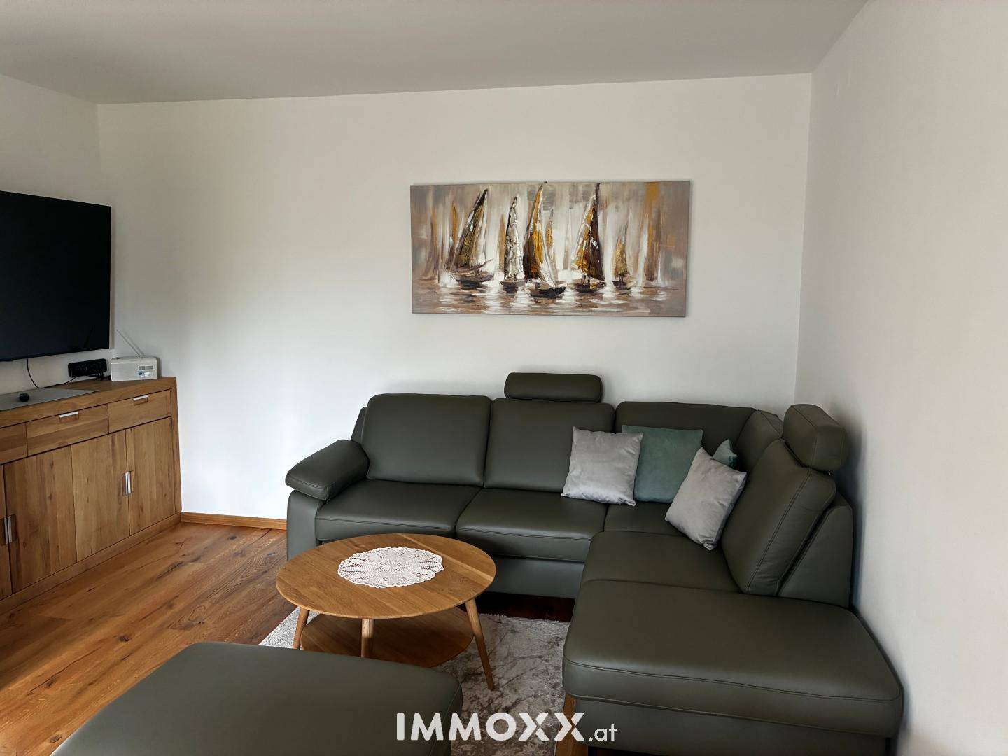 Gemütliches Wohnzimmer mit Ecksofa, Holzboden und modernem Wandbild über dem Sofa.