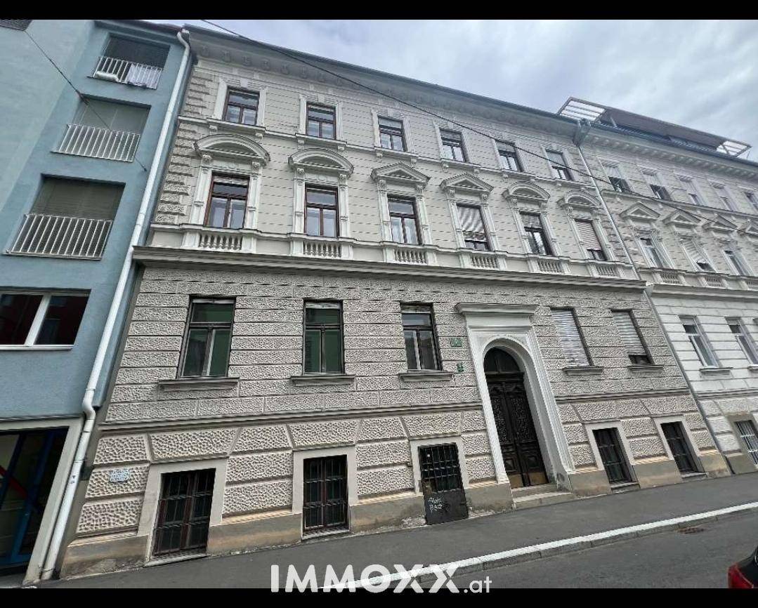 Historische Fassade eines Mehrfamilienhauses mit reich verzierten Fenstern und Eingangsbereich.