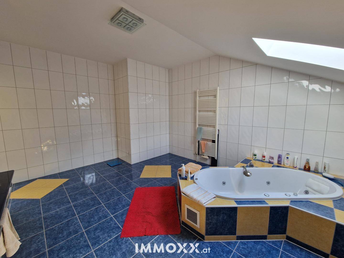 Badezimmer mit blauen und gelben Fliesen, Eckbadewanne mit Whirlpoolfunktion und Dachschräge.