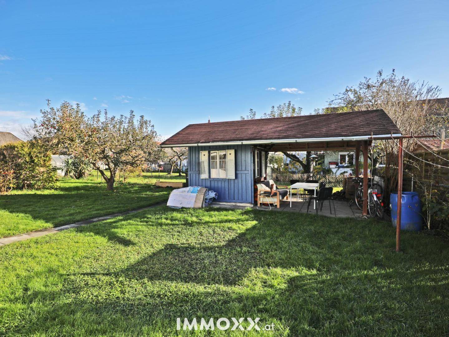 Gemütlicher Gartenpavillon mit überdachtem Sitzbereich und umgebender Rasenfläche.