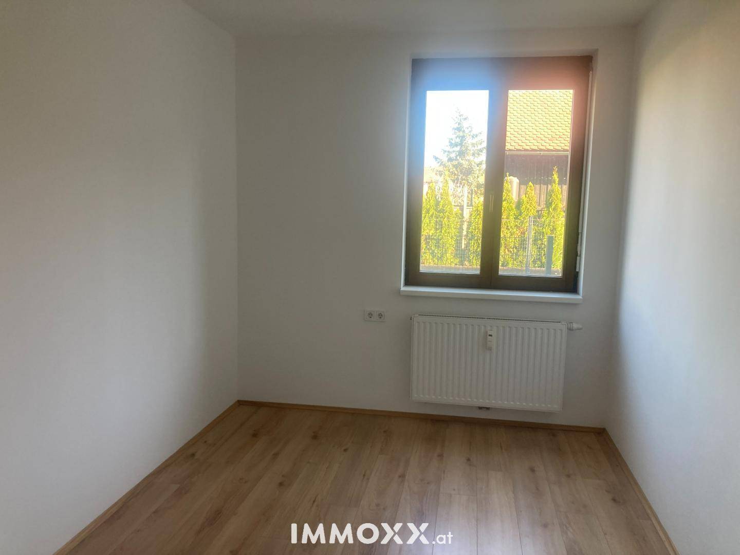 Freundlicher Raum mit Laminatboden und einem Fenster, das viel natürliches Licht bietet.