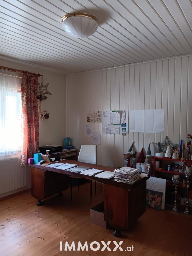 Arbeitszimmer mit Holzvertäfelung an der Decke, Holzboden und großem Schreibtisch.