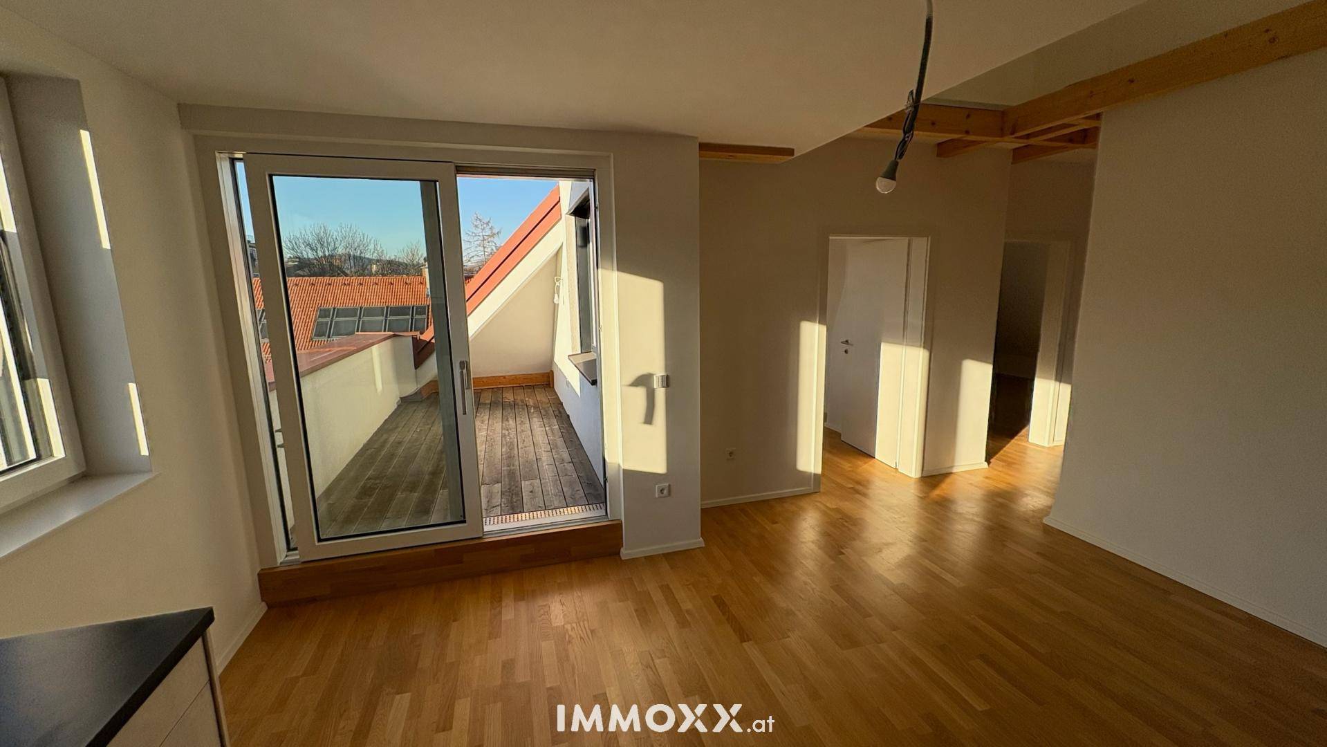 Lichtdurchfluteter Wohnbereich mit Holzboden und Zugang zu einer sonnigen Dachterrasse.