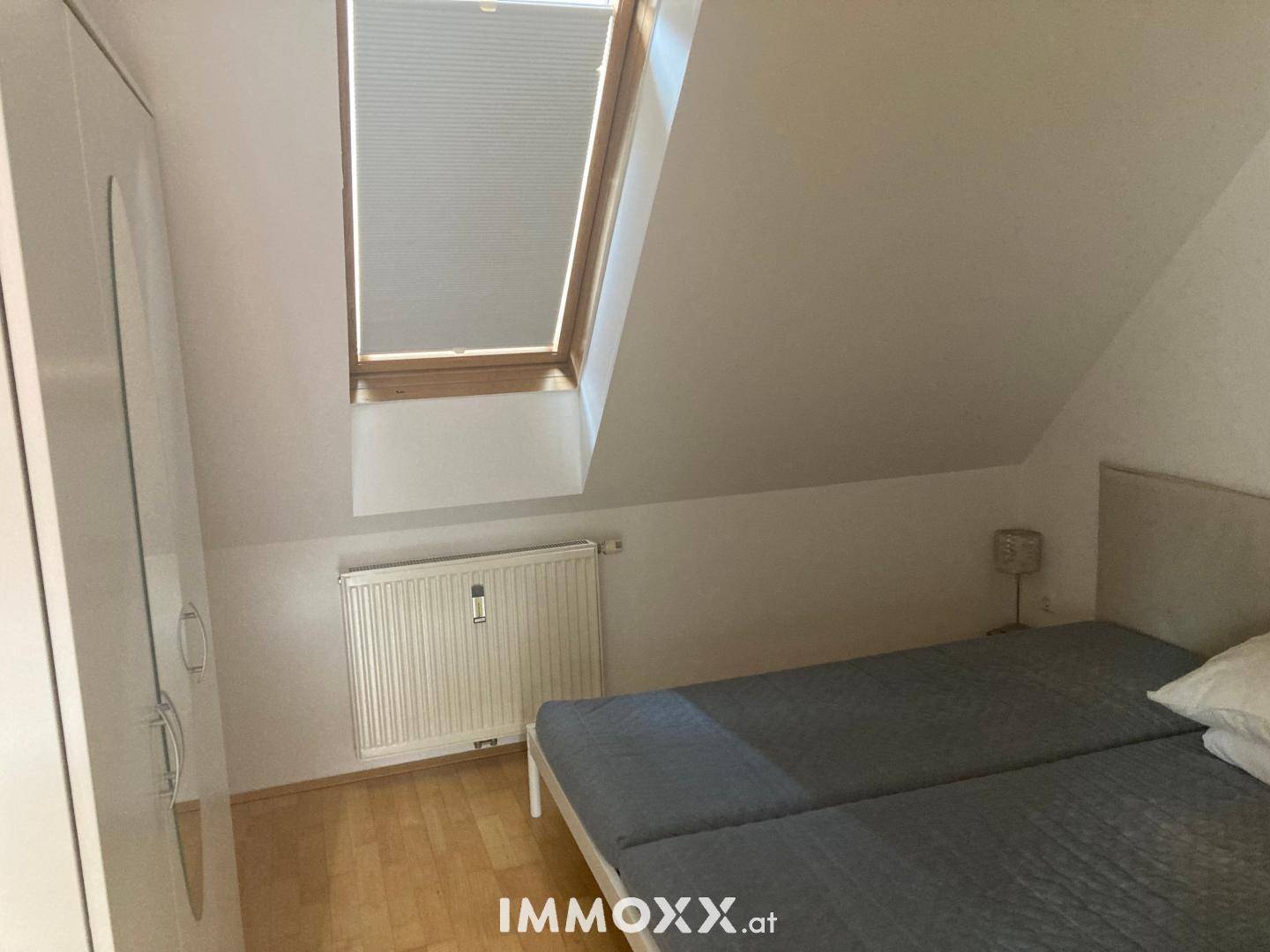 Schlafzimmer im Dachgeschoss mit Einzelbett, Kleiderschrank und einem Dachfenster.