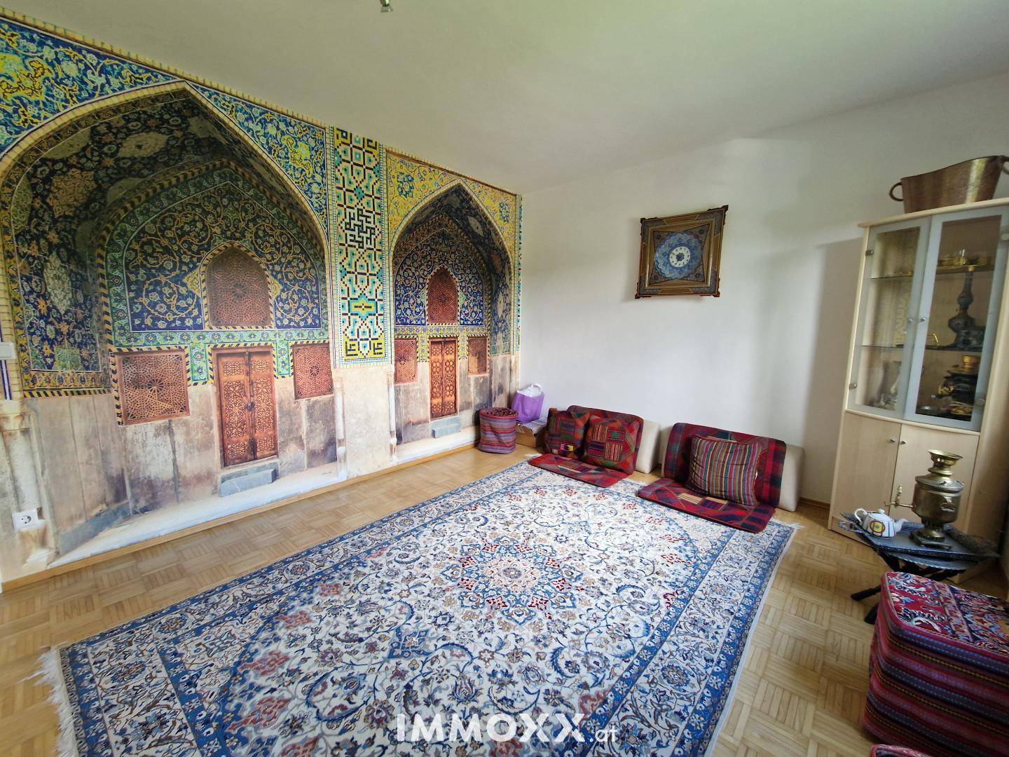 Raum mit orientalischem Wandbild, großem Teppich und Bodenkissen, der eine einzigartige Atmosphäre schafft.