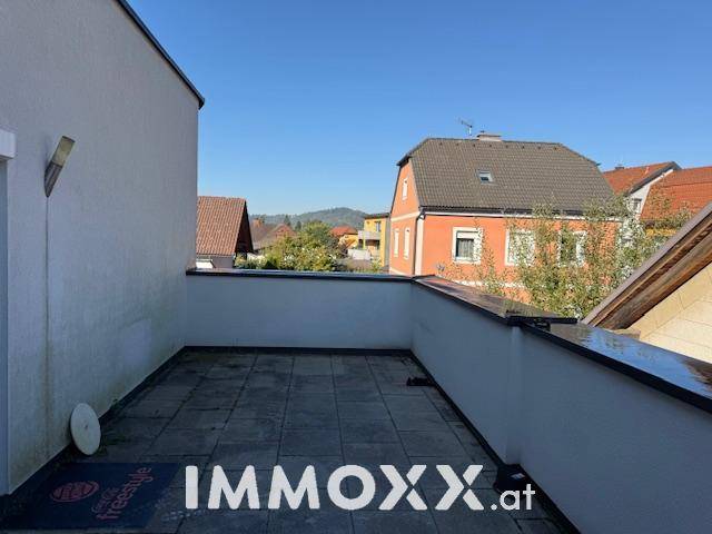 Geräumige Dachterrasse mit Fliesenboden und Blick auf die umliegenden Häuser.