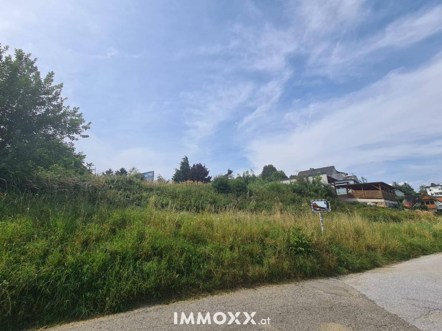 Weitläufiges, bewachsenes Grundstück mit Blick auf umliegende Häuser und eine weite Himmelslandschaft.