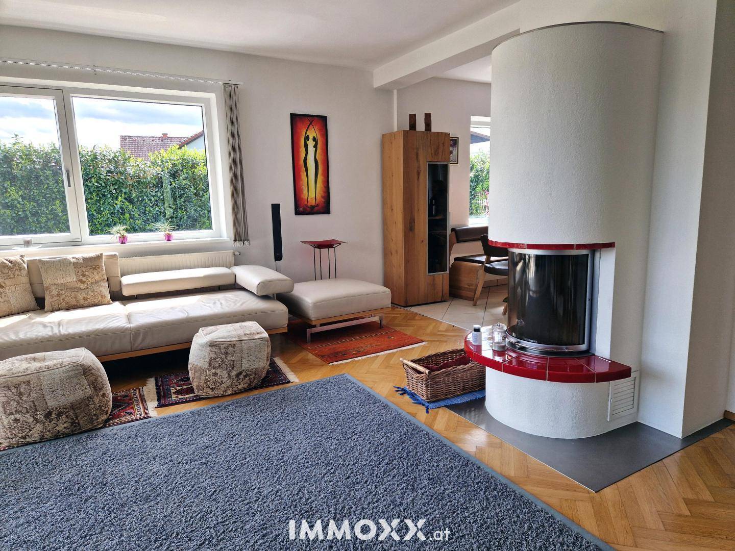 Gemütliches Wohnzimmer mit modernem Kaminofen, beigem Sofa und Fischgrätparkettboden.