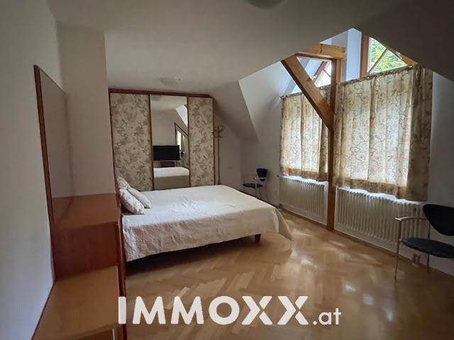 Geräumiges Schlafzimmer im Dachgeschoss mit Parkettboden, Spiegelschrank und Holzbalken.