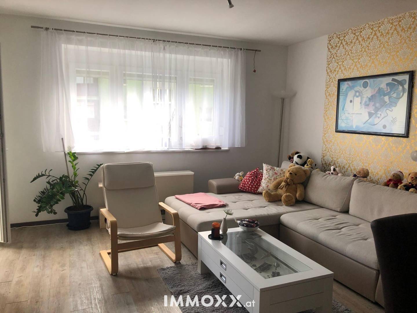 Helles Wohnzimmer mit beigem Sofa, Couchtisch und dekorativer Tapete an einer Wand.