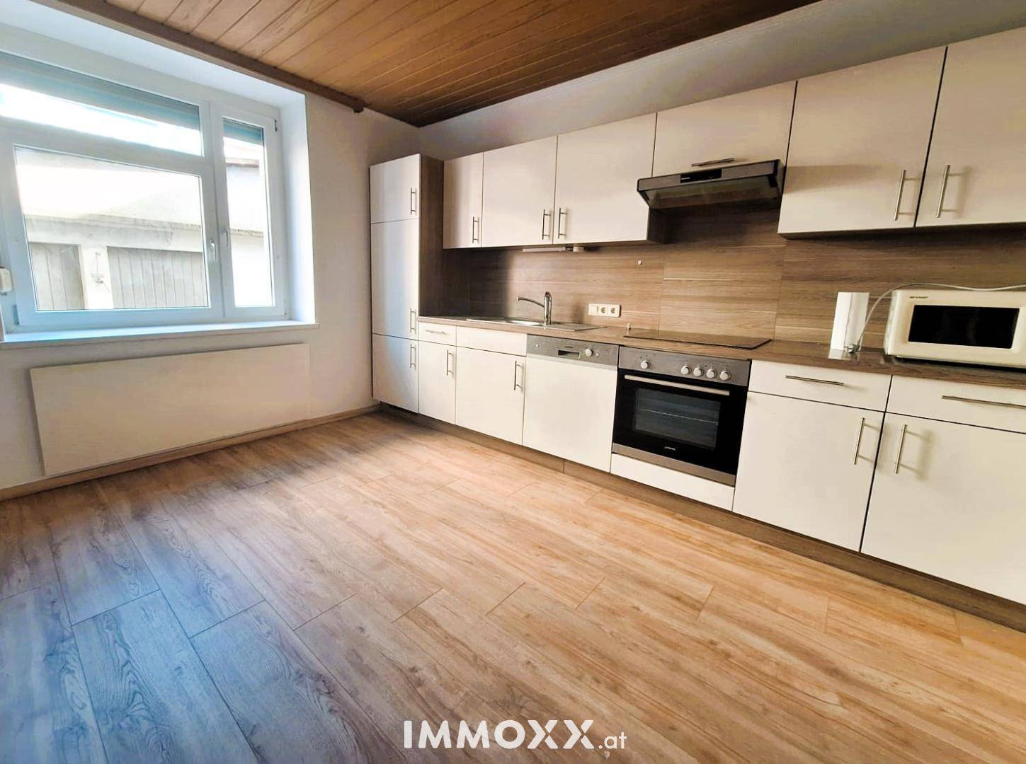 Geräumige Küche mit Einbaumöbeln, Laminatboden und großem Fenster für viel Tageslicht.