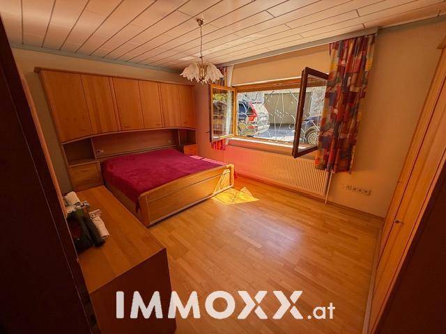 Gemütliches Schlafzimmer mit Holzboden, Einbauschränken und einem Fenster mit Blick nach draußen.