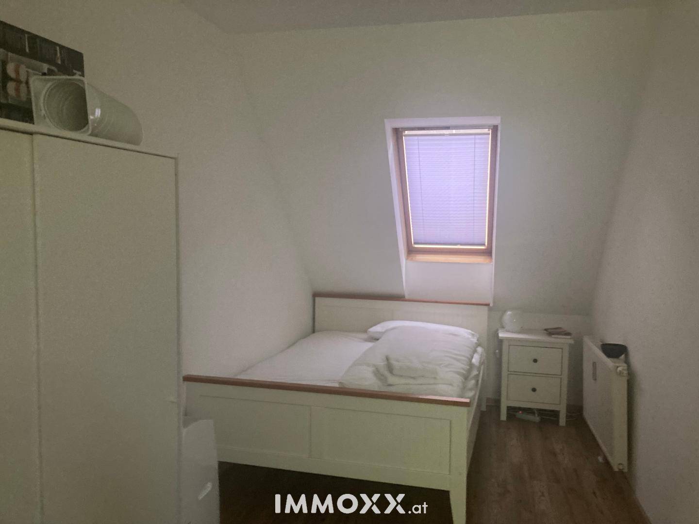 Schlafzimmer im Dachgeschoss mit Bett, Kleiderschrank und Dachfenster, hell und funktional.