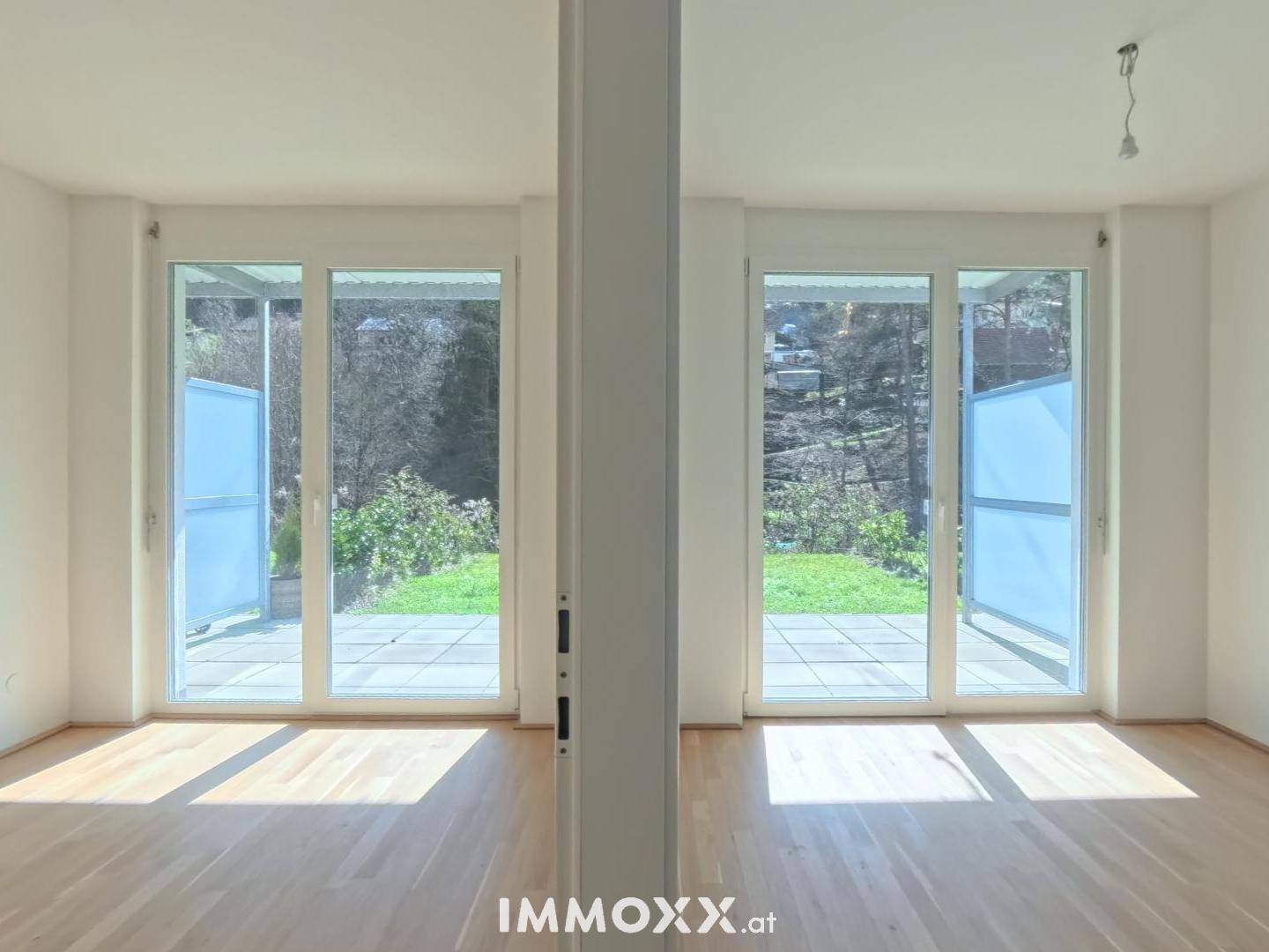 Heller Wohnbereich mit zwei großen Fenstertüren und Zugang zur Terrasse oder Garten.
