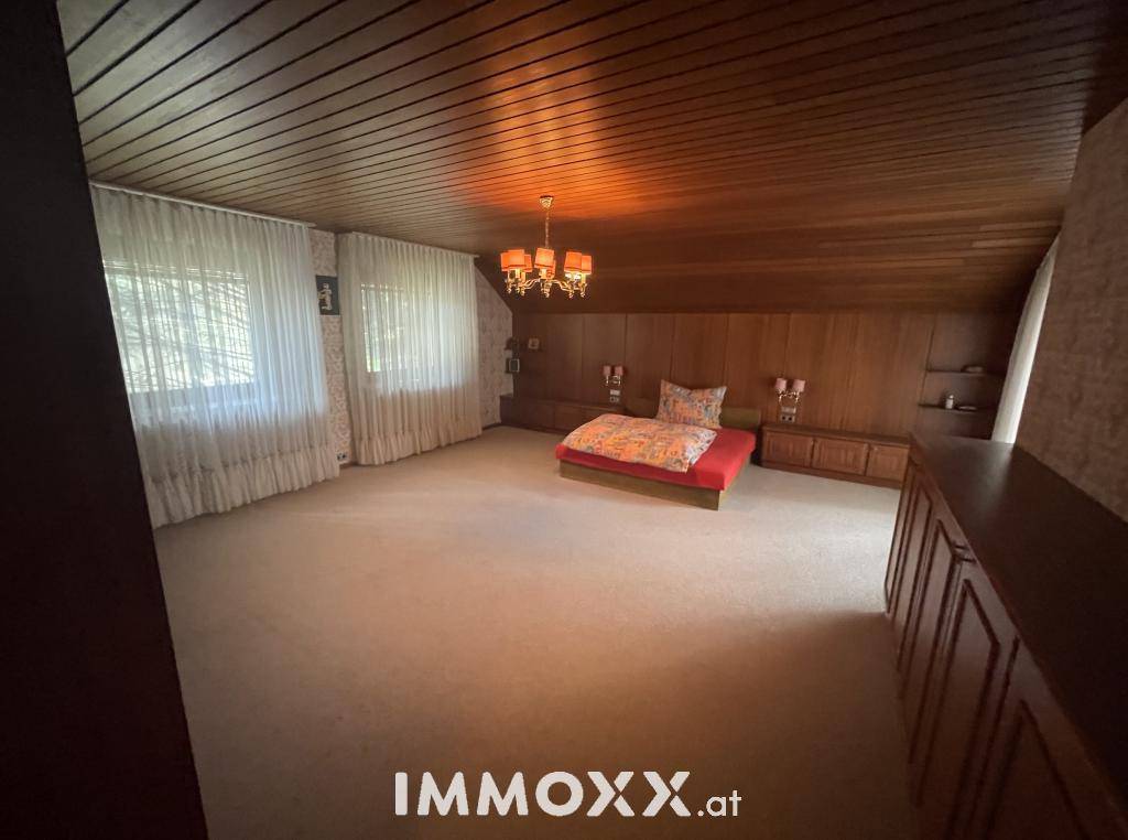 Geräumiges Schlafzimmer mit Teppichboden, Holzvertäfelung und großem Bett.