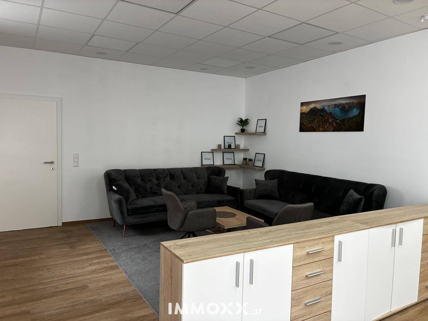 Gemütlicher Loungebereich mit dunklen Sofas und einem Holztisch, ideal für Pausen oder informelle Besprechungen.