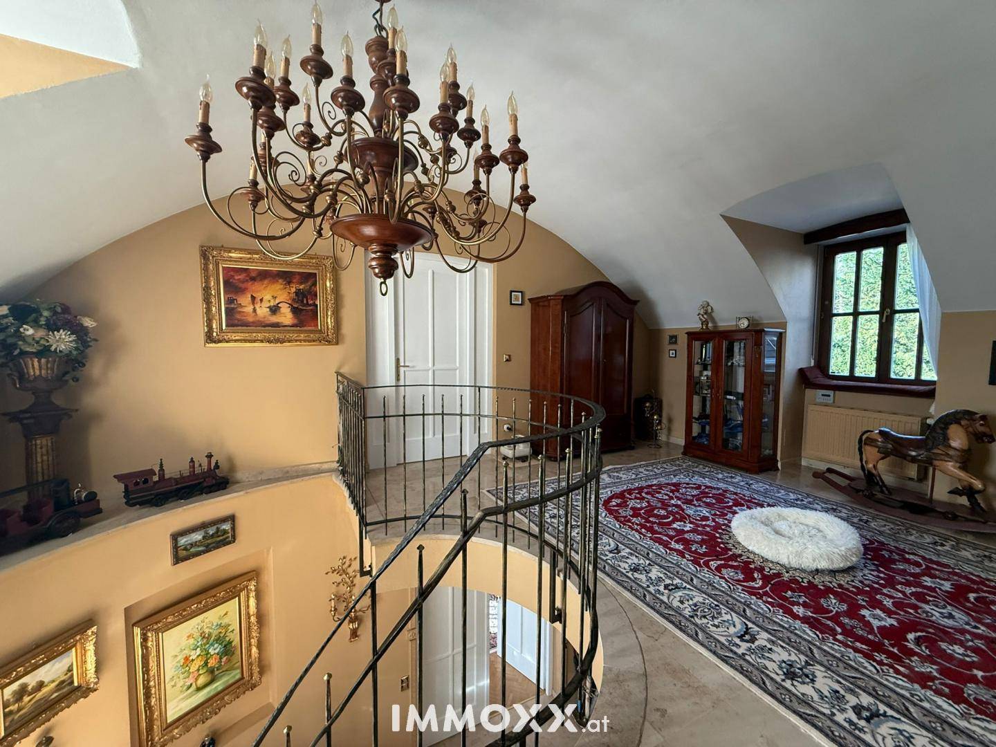 Obergeschoss-Flur mit eleganter Wendeltreppe, opulentem Kronleuchter und traditioneller Dekoration.
