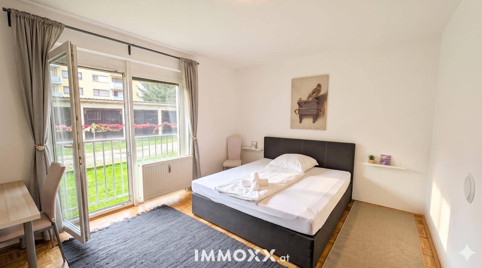 Schlafzimmer mit Doppelbett, Schreibtisch und direktem Zugang zum Außenbereich.