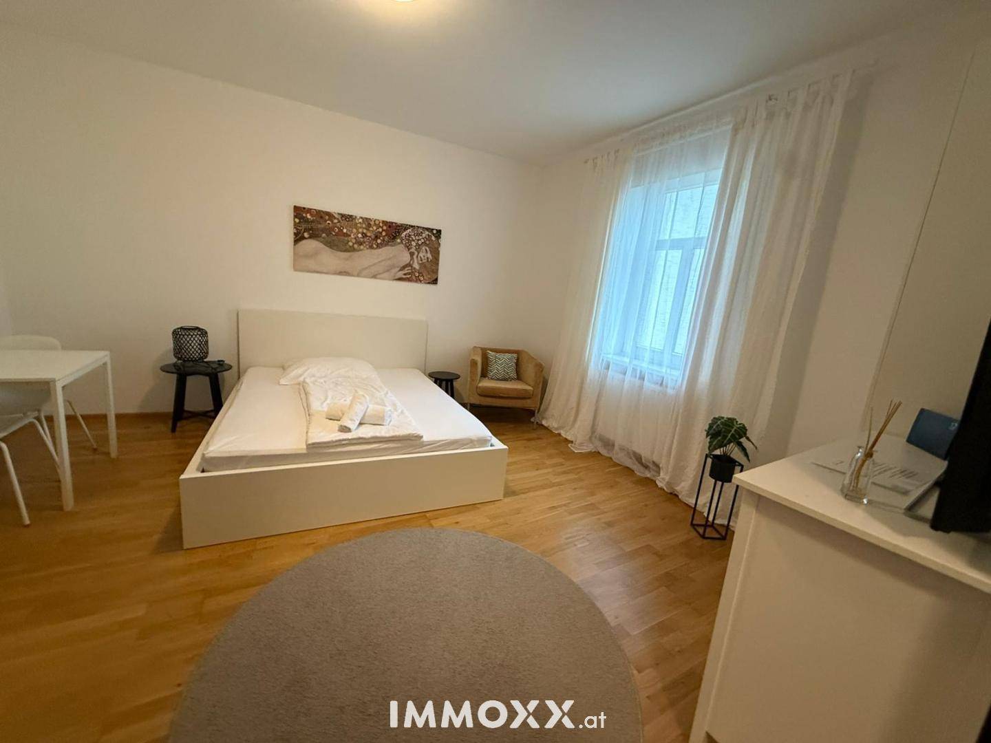 Geräumiges Schlafzimmer mit Doppelbett, Holzboden und großem Fenster für viel natürliches Licht.