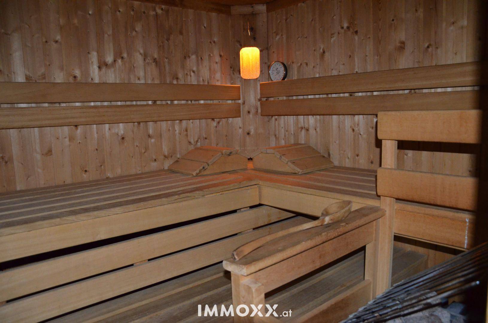 Traditionelle Holzsauna mit mehreren Bänken und einer warmen, gedämpften Beleuchtung für Entspannung.