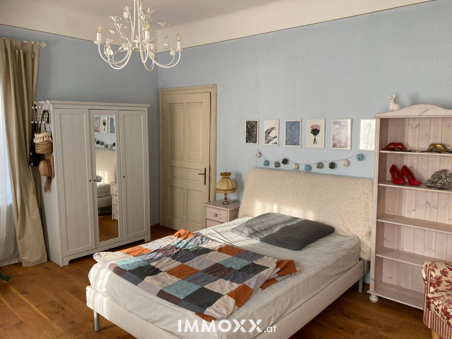 Helles Schlafzimmer mit blau gestrichenen Wänden, Holzboden und weißem Kleiderschrank.