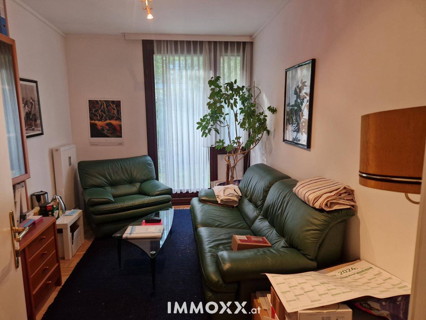 Wohnzimmer oder Wartebereich mit grünen Ledersofas und großem Fenster.
