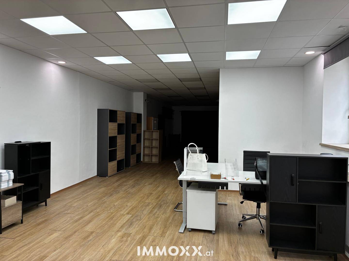 Helles und offenes Büro mit Holzfußboden und Regalsystemen, bereit zur individuellen Gestaltung und Nutzung.