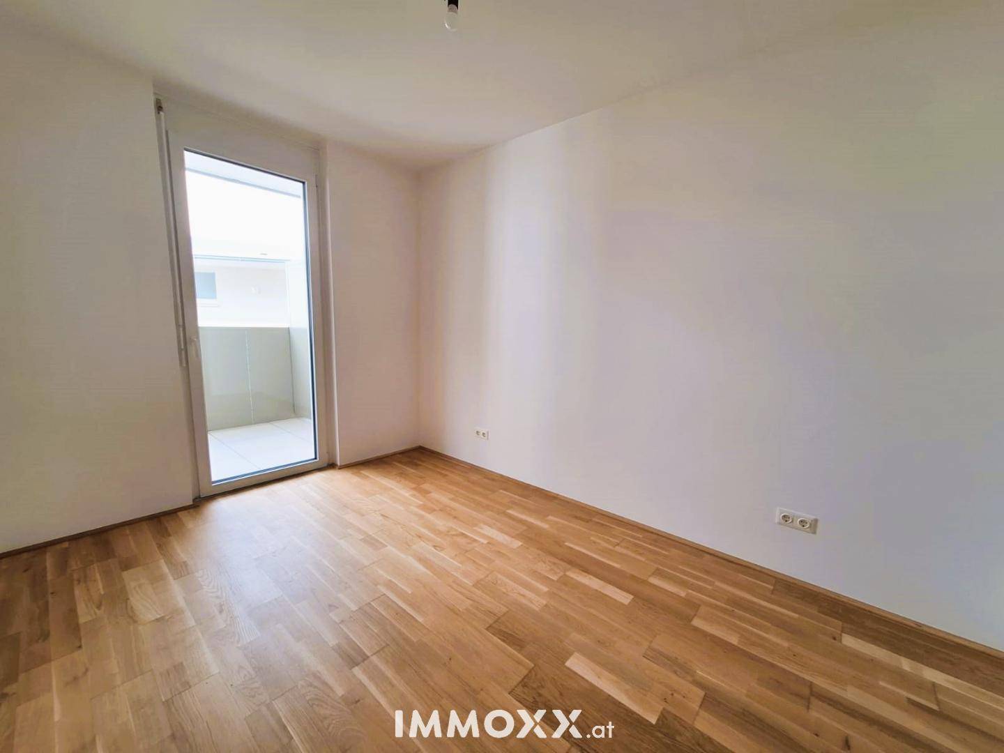 Helles Schlafzimmer mit Holzboden und Zugang zu einem Balkon, ideal für frische Luft.
