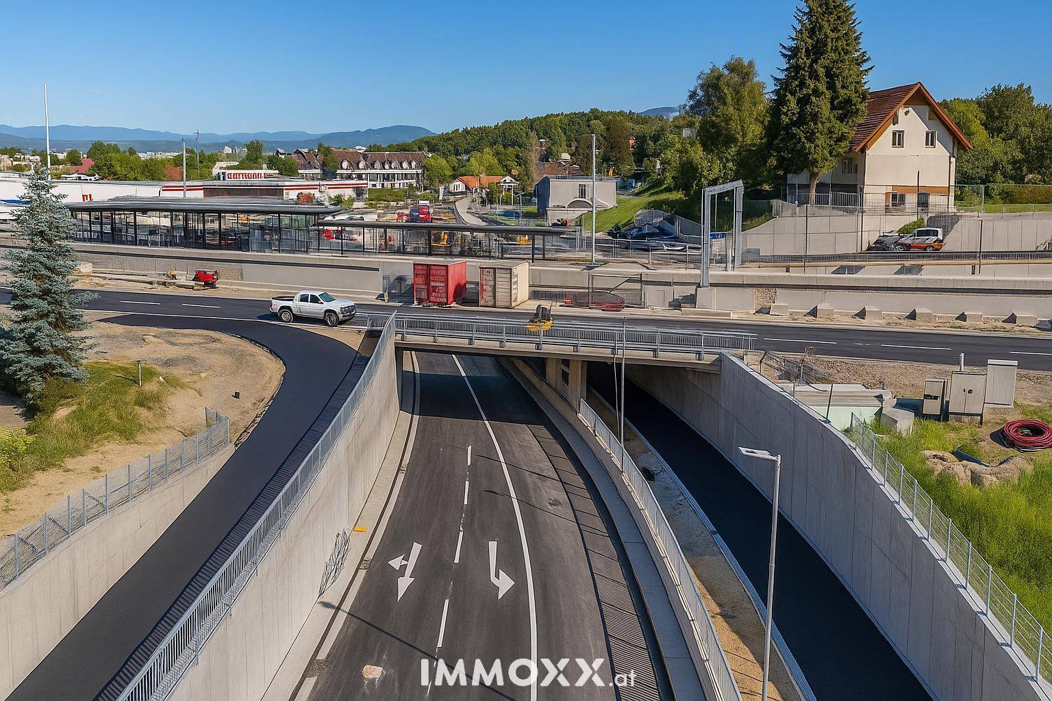 Luftaufnahme einer Straßenunterführung mit einem Bahnhof im Hintergrund und umliegender Bebauung.