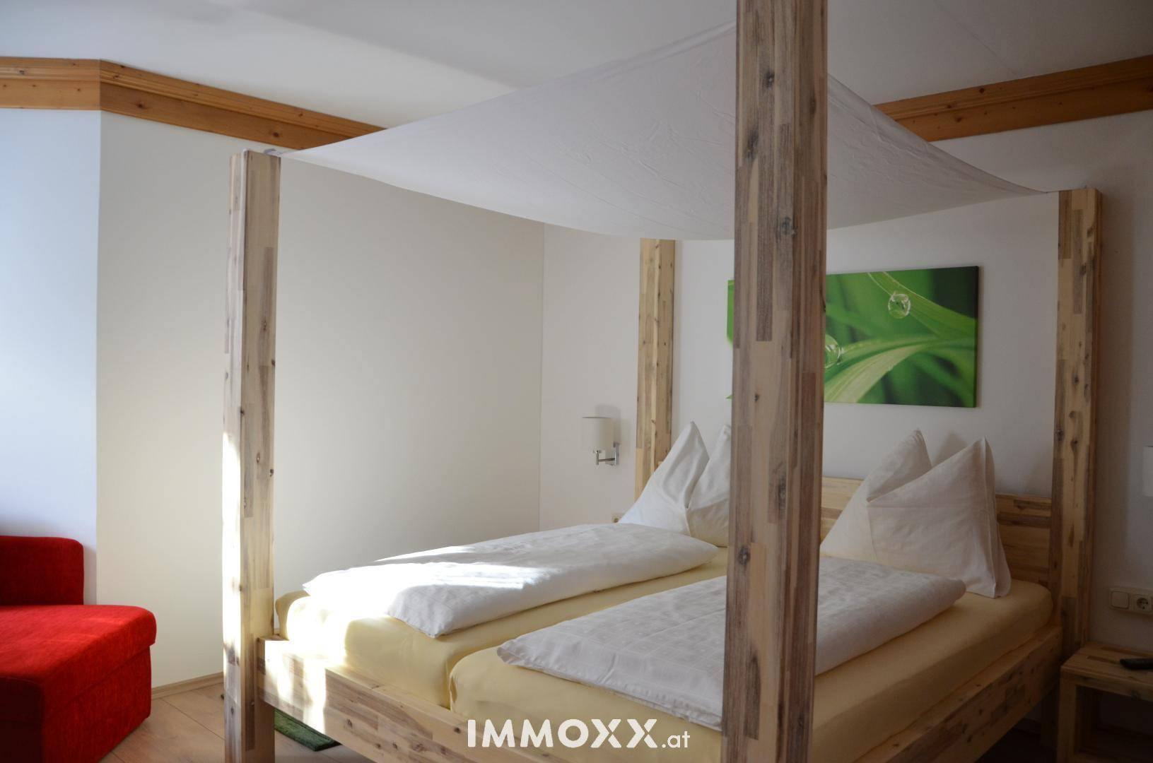 Geräumiges Schlafzimmer mit einem Himmelbett aus Holz und einem modernen Wandbild mit Naturmotiv.