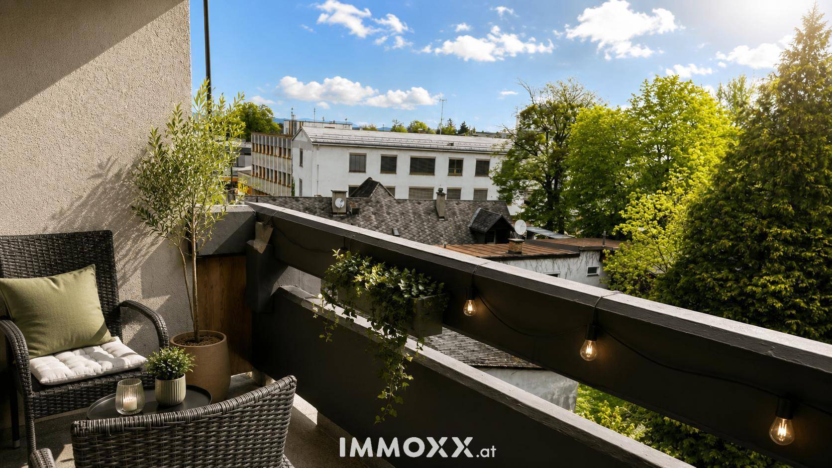 Möblierter Balkon mit Pflanzen und Lichterkette, bietet Blick auf die Umgebung.