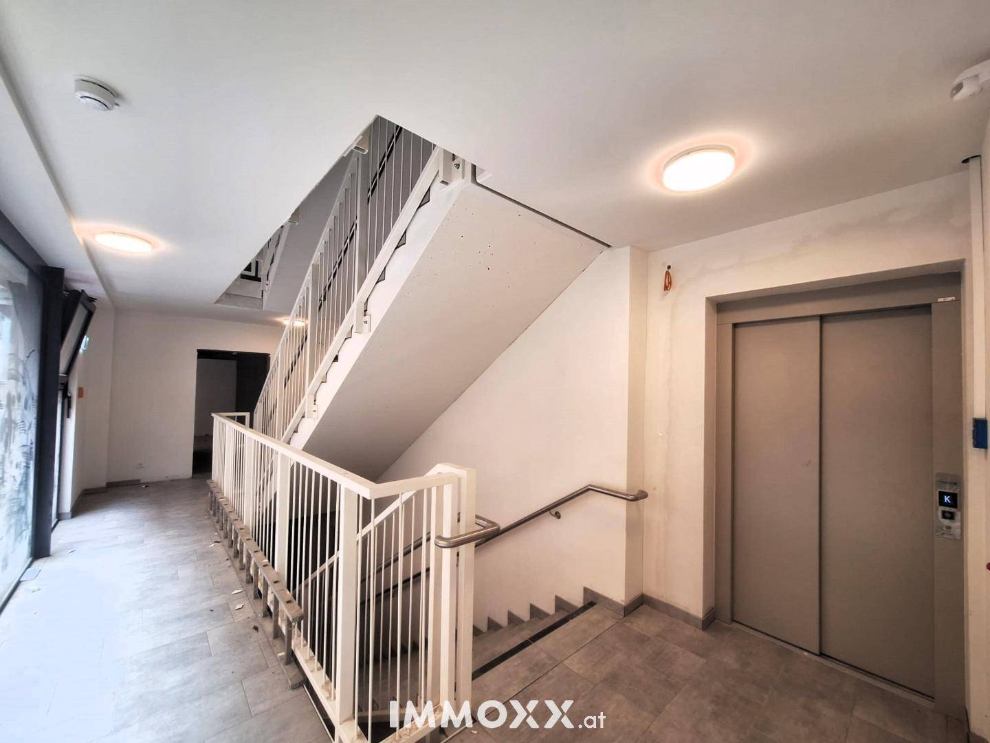 Heller Eingangsbereich mit Treppenhaus und modernem Aufzug in einem Mehrfamilienhaus.