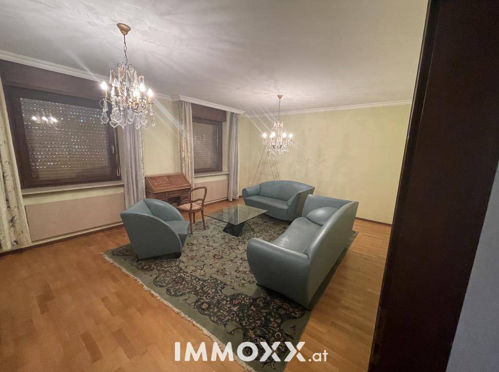 Helles Wohnzimmer mit Parkettboden, eleganten Sofas und Kronleuchtern.