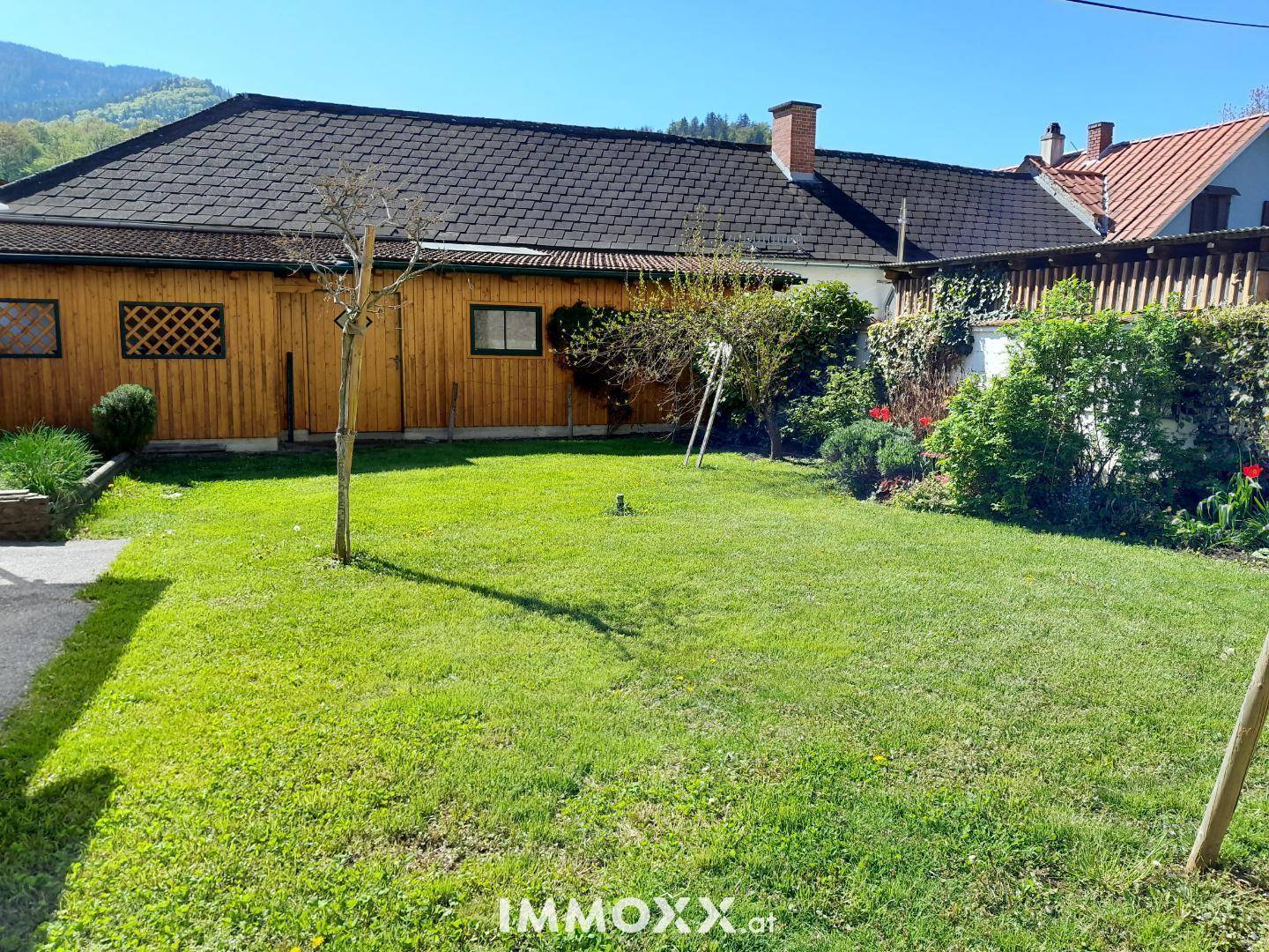Gepflegter Garten mit Rasenfläche, Sträuchern und Blick auf die umliegende Natur.