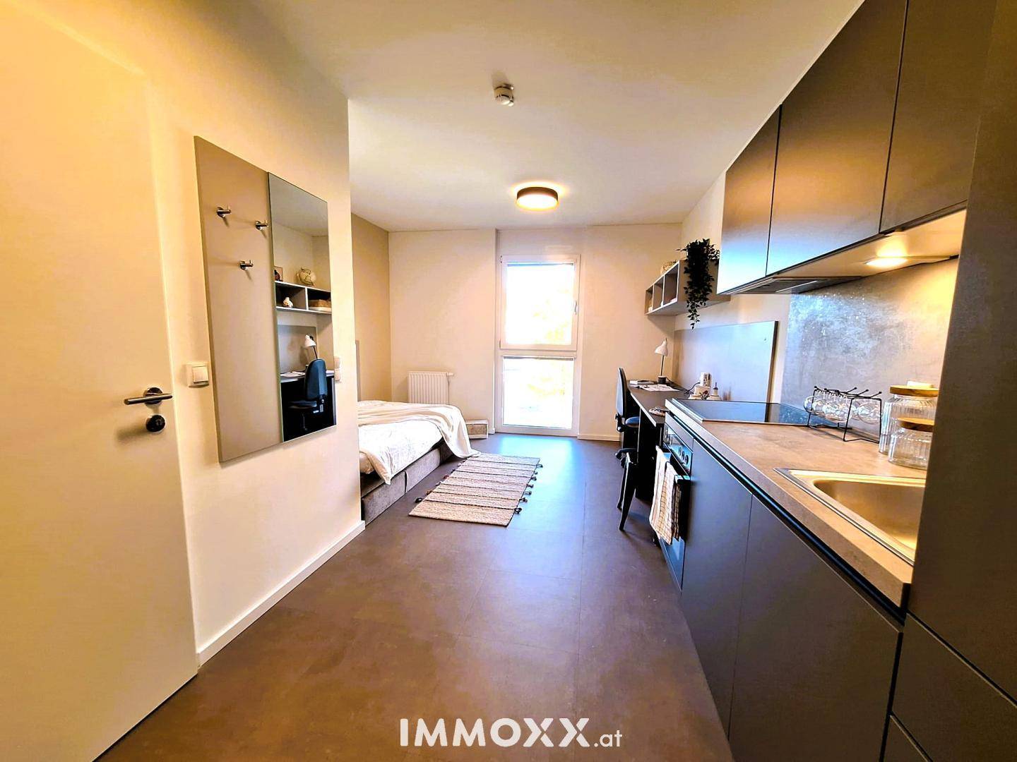Kompaktes Studio-Apartment mit Küchenzeile, Schlafbereich und Arbeitsplatz in modernem Design.