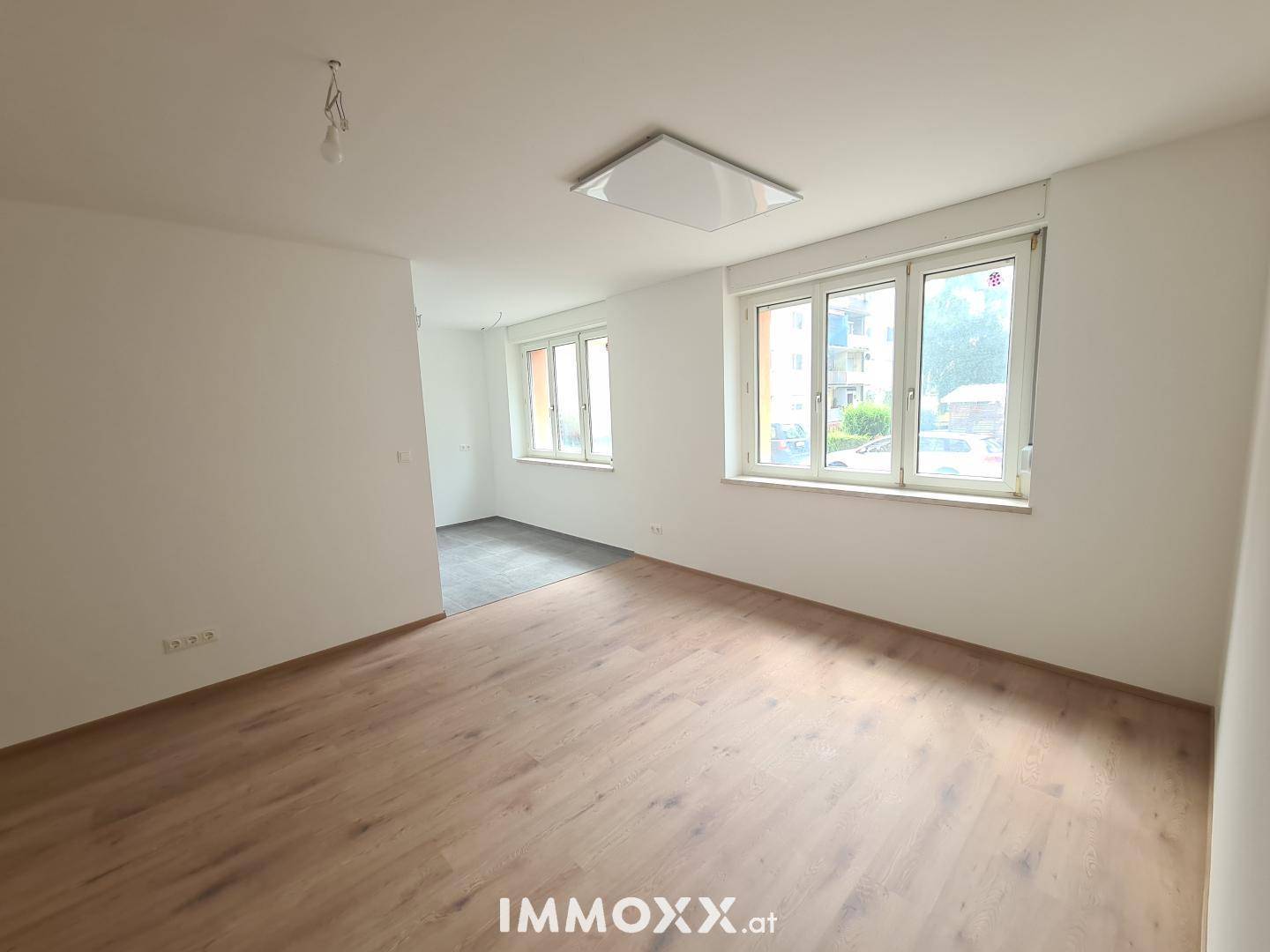 Geräumiges, helles Zimmer mit Laminatboden und Blick ins Grüne durch die Fenster.