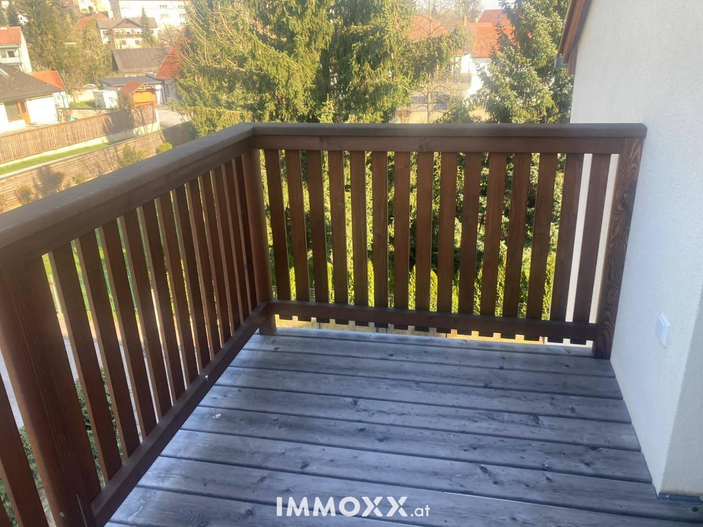 Gemütlicher Holzbalkon mit Blick ins Grüne, ideal für entspannte Stunden im Freien.