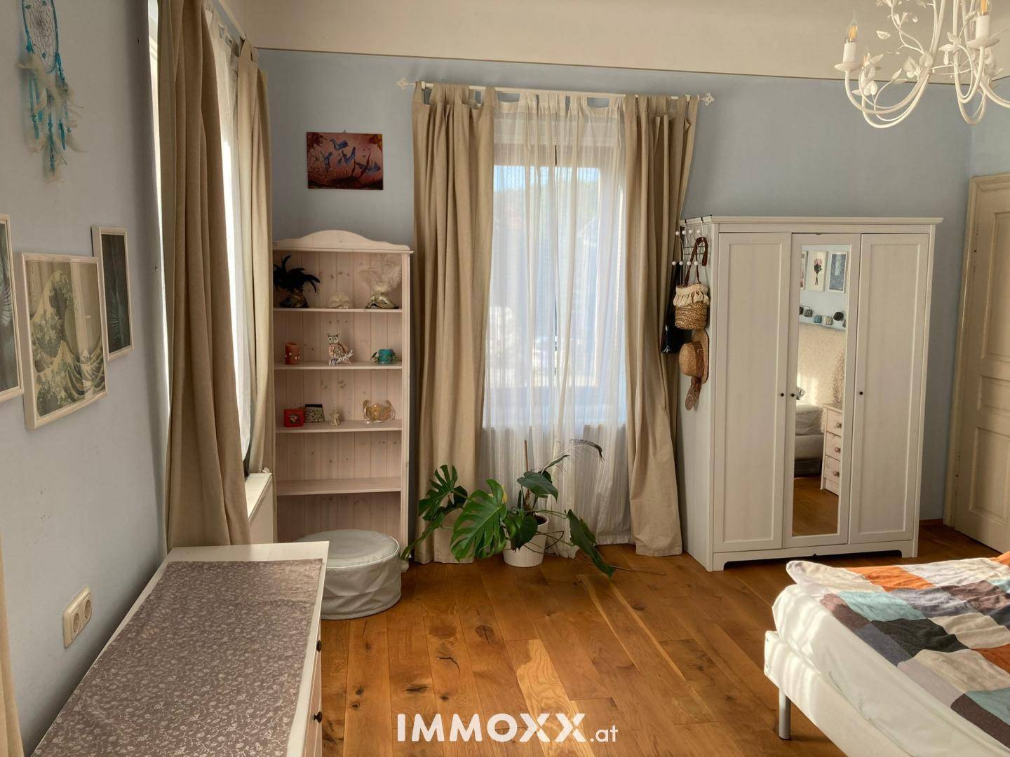 Geräumiges Schlafzimmer mit Holzboden, großem Fenster und weißem Kleiderschrank.